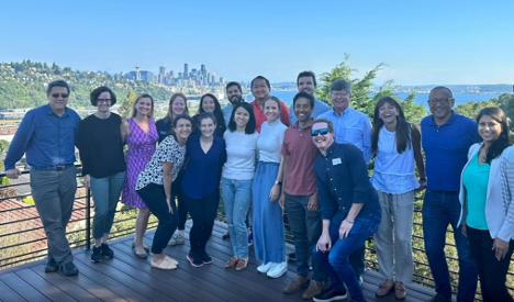 Group of 15 faculty and fellows on a sunny evening with the Seattle skyline in the background