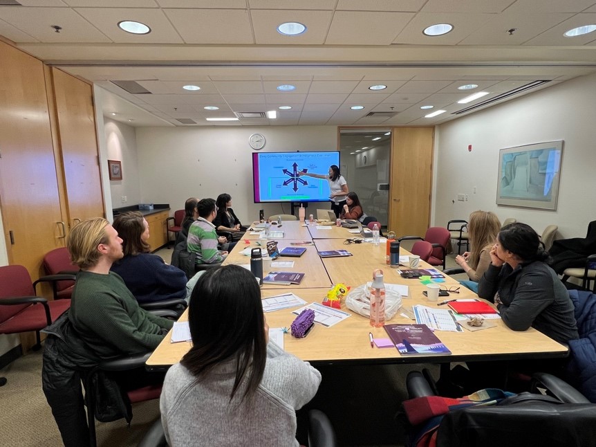 Group of people around conference tables following a speaker